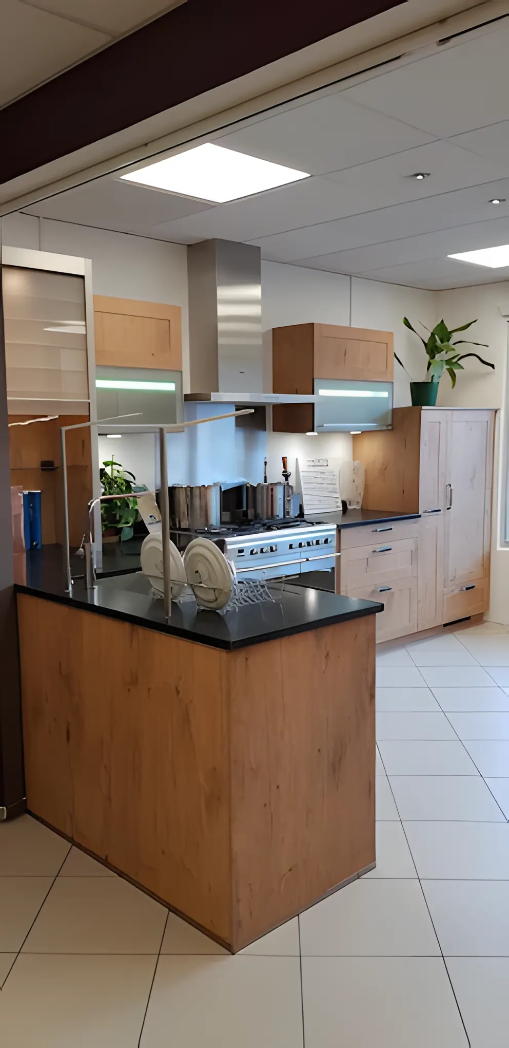 Îlot en bois à plan noir exposé au showroom de Cuisines Giros, cuisine bois et inox en arrière-plan
