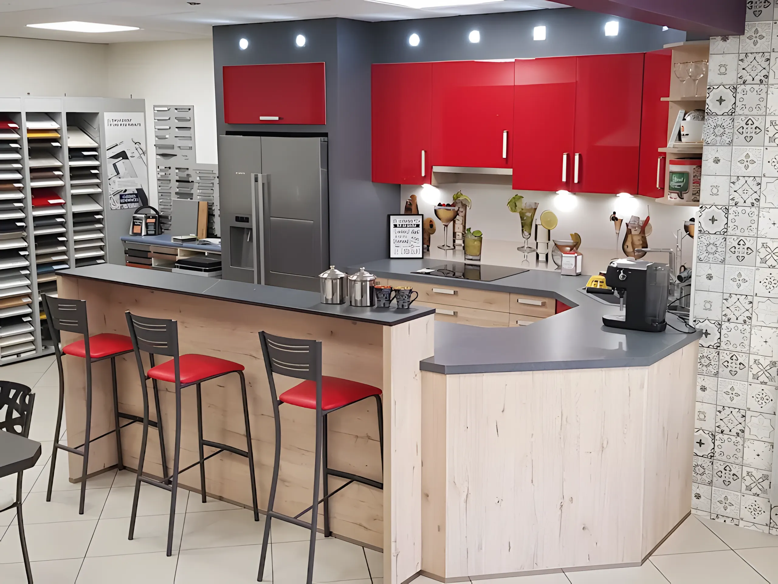 Cuisine exposée au showroom : façades laquées rouges, îlot bar en bois clair et tabourets rouges